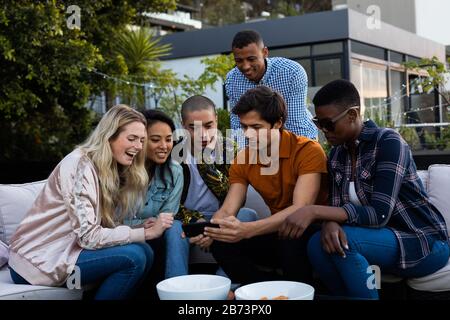 Gruppe gemischter Rennfreunde, die gemeinsam ein Telefon ansehen Stockfoto