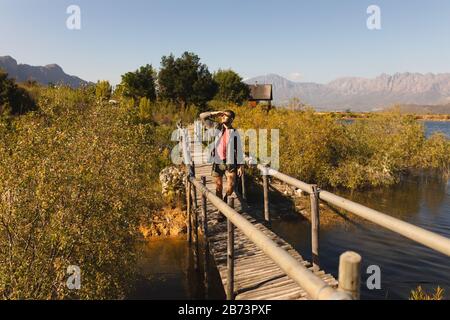 Vorderansicht des Menschen, der auf einer Holzbrücke spazieren geht Stockfoto