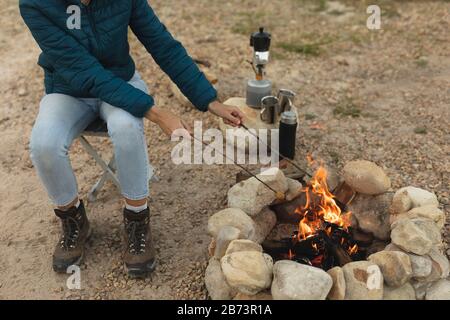 Hochwinkeliger Blick auf Frau, die Würstchen im Feuer kocht Stockfoto