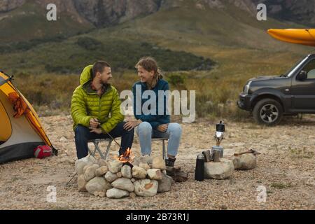 Vorderansicht des Paares, das vor dem Feuer sitzt Stockfoto