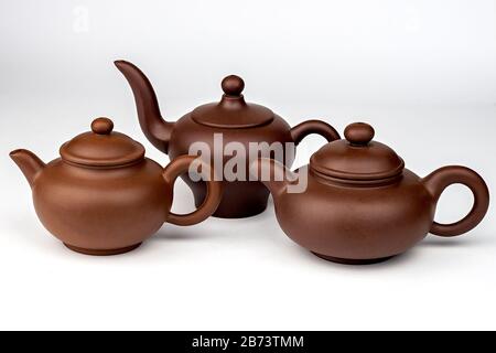 Satz aus drei braunen Tonteapots, isoliert auf weißem Grund. Stockfoto