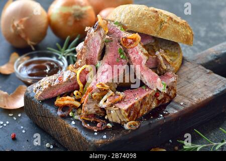 Burger mit saftigen Fleischstreifen aus Rinderloinsteak und gebratenen Zwiebelringen Stockfoto