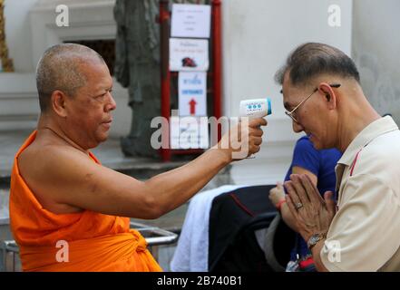 Bangkok, Thailand. März 2020. Der buddhistische Mönch überprüft die Temperatur der Touristen als Vorsichtsmaßnahme gegen den Ausbruch des Coronavirus Covid-19 im Wat Pho in Bangkok am 13. März 2020. Die Viruserkrankung COVID-19, die in mindestens 114 Länder gefegt und mehr als 4.000 Menschen getötet hat, ist jetzt offiziell eine Pandemie, teilte die Weltgesundheitsorganisation mit. Kredit: Urdee Image/ZUMA Wire/Alamy Live News Stockfoto