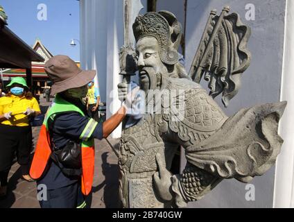 Bangkok, Thailand. März 2020. Thailändischer Beamter reinigt die alte Statue vorsorglich gegen den Ausbruch des Coronavirus Covid-19 im Wat Pho in Bangkok am 13. März 2020. Die Viruserkrankung COVID-19, die in mindestens 114 Länder gefegt und mehr als 4.000 Menschen getötet hat, ist jetzt offiziell eine Pandemie, teilte die Weltgesundheitsorganisation mit. Kredit: Urdee Image/ZUMA Wire/Alamy Live News Stockfoto