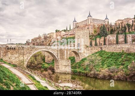 Stadtbild von Toledo in Spanien mit dem Fluss Tejo und der römischen Brücke Puente de Alcantara. Berühmtes UNESCO-Weltkulturerbe. Die historische Stadt in hdr Art Stockfoto