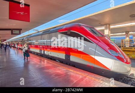 FLORENZ ITALIEN PASSAGIERE AUF DEM BAHNSTEIG UND DER TRENITALIA-ZUG, DER AM BAHNHOF EINE ROTE SCHNELLFAHRSTRECKE FRECCIAROSSA 09-B ANFÄHRT Stockfoto