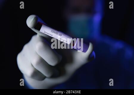 Wissenschaftler im Schutzanzug mit Coronavirus-Reagenzglas. Kovid 19 Stockfoto
