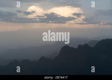Blick über die hazigen Simien-Berge am frühen Abend mit Sonne, die durch verstreute Wolken über dem Kopf bricht, Amhara-Region, Äthiopien Stockfoto