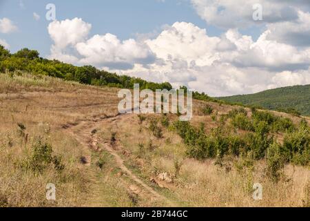 Leere schmutzige Landstraße in schlechtem Zustand. Krimberge am sonnigen Tag, Landschaftsfoto-Hintergrund Stockfoto