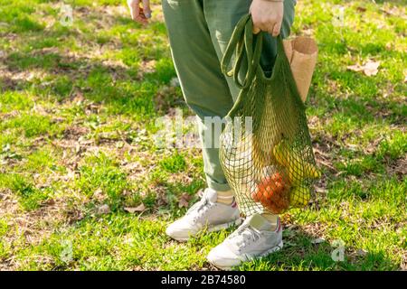 Weibliche Hand mit organischer Tomate, apfel, Banane und französischem Baguette in einer Netztasche ohne Abfall Stockfoto