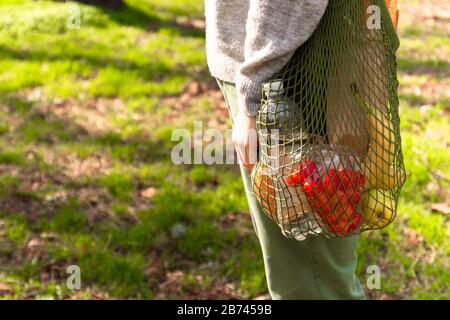 Tragetasche aus grüner Öko-Baumwolle mit Bio-Lebensmitteln. Bio-Tomaten, Bananen, Äpfel, Brot und Käse. Pflege der Natur Stockfoto