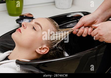 Haarstylisten, die Haarmastbehandlung auf nassem Haar in einem Waschtisch anwenden. Stockfoto