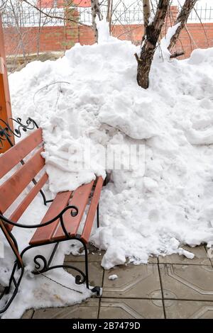Viel Schnee auf einer Bank im Winter. Sonniger Tag ohne Niederschlag. Schnee muss beseitigt werden. Stockfoto