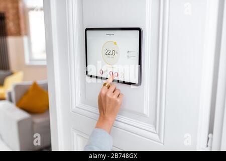 Temperaturregelung im Wohnzimmer mit einem digitalen Touchscreen. Konzept der Heizungssteuerung in einem intelligenten Zuhause Stockfoto