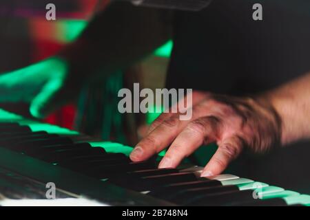Hände eines Pianisten oder Keyboarders einer Rockband schließen sich dem Spielen eines Synthesizers an. Selektiver Fokus Stockfoto