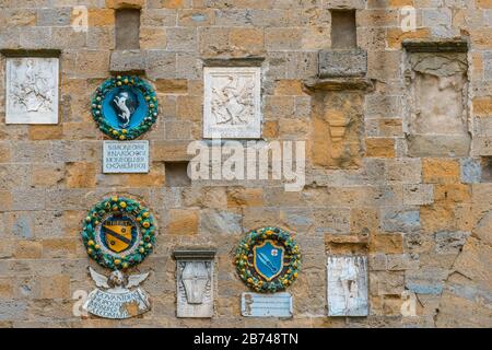 Mittelalterlichen Wappen einheimischer Adelsfamilien an einer Steinmauer in der historischen Altstadt von Volterra, Toskana, Italien. Stockfoto