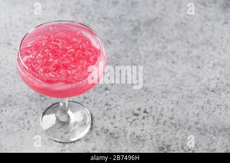 Schimmernder essbarer Glitzer Rosengwein garniert Rosmarin auf Grau. Nahaufnahme. Leerzeichen für Text. Stockfoto