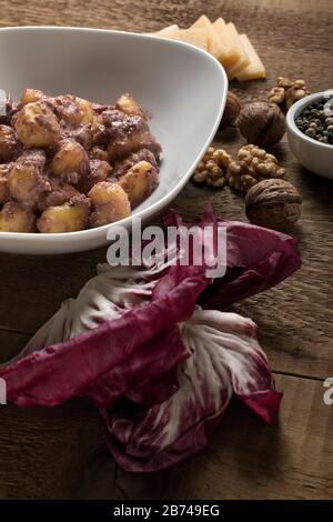 Glutenfreie Kartoffelklöße mit Radicchio Sauce, Walnüssen, Pfeffer und Parmesankäse. Stockfoto