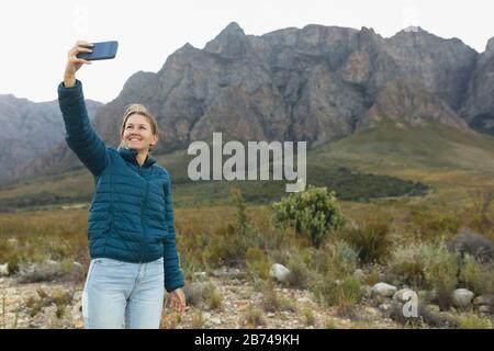 Vorderansicht der Frau, die Selfies vor einem Berg nimmt Stockfoto
