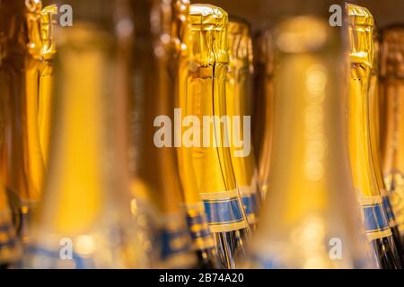 Nahaufnahme von vielen/einer Gruppe versiegelter Champagner-/Sekt-Flaschen. Goldfarbene Folie mit blauem Streifen. Kein Logo. Zum Feiern, Feiern usw. Stockfoto