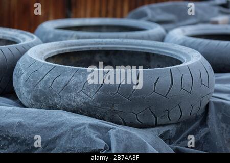 Nahaufnahme eines Stapels gefrorener/vereister Reifen. Außerhalb der Wintersaison gelagert. Wegen der kalten Witterung komplett von Eis bedeckt. Alte Reifen. Stockfoto