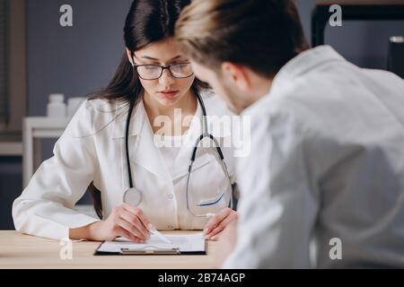 Arzt in einer Brille, der den Behandlungsplan des Patienten erläutert Stockfoto