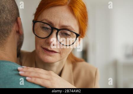Nahaufnahme der rothaarigen Frau in Brillen, die den Mann umarmte, während sie im Raum standen Stockfoto