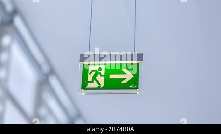 Blick auf das beleuchtete Notausgangsschild. Mit laufender Abbildung und Pfeil nach rechts. Neutraler, weißer Hintergrund. Modernes Design. Stockfoto