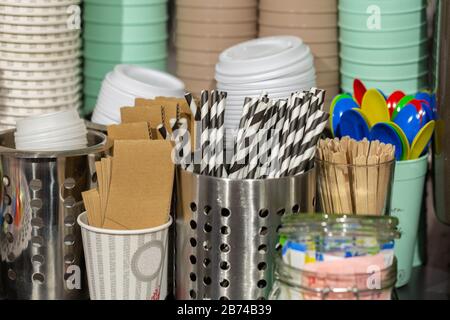 Möchten Sie etwas Kaffee trinken? Die Ausrüstung, die Sie brauchen, ist da: Gestreifte Trinkhalme, Kaffeetassen, Deckel, Holzstöcke, Plastiklöffel. In einem Café. Stockfoto