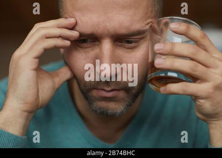 Trauriger reifer Mann mit einem Glas Alkohol trinkt, hat Probleme bei der Arbeit Stockfoto