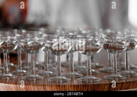 Viele elegante leere Gläser Wein oder Champagner auf dem Holztisch am Hochzeitstag. Satz leerer Brillen, die in Zeilen angezeigt werden. Vorbereitung für den Stockfoto