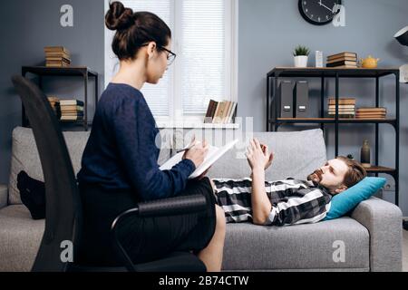 Kompetenter Psychologe, der einen bärtigen Patienten im Büro hört Stockfoto
