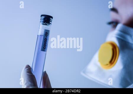 Weibliche Medizin- oder Forschungswissenschaftlerin, die ein Reagenzglas mit einem Kovid19-Etikett hält Stockfoto