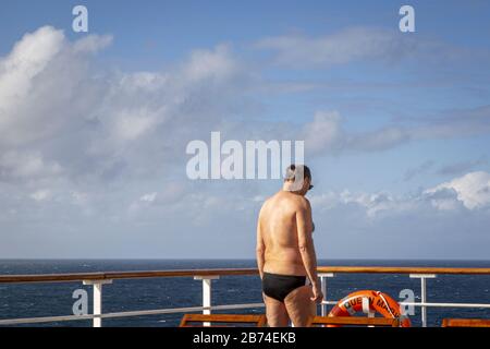 Überqueren Sie den Atlantik von Brooklyn nach Southampton an Bord des Ozeanliners Queen Mary 2. Passagiere, die auf dem Hauptdeck die Sonne aufnehmen. Stockfoto