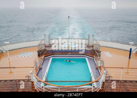Überqueren Sie den Atlantik von Brooklyn nach Southampton an Bord des Ozeanliners Queen Mary 2. Ein einsamer Schwimmer im Schwimmbad auf dem hinteren Hauptdeck.