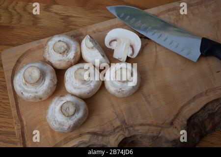 Gemeine weiße Pilze auf einem Hackbrett mit einem Messer Stockfoto