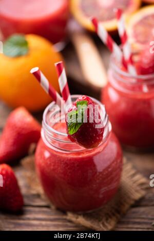 Erdbeer-Smoothie im Glasbecher, über altem Holztisch. Nahaufnahme Stockfoto