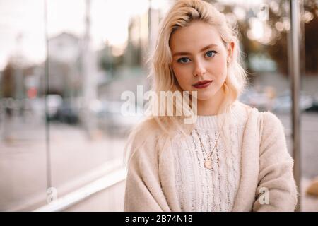 Porträt der jungen selbstbewussten Frau, die auf einer Bushaltestelle in der Stadt steht Stockfoto