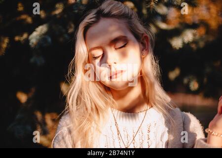 Porträt der jungen Frau mit geschlossenen Augen vor Sonnenlicht Stockfoto
