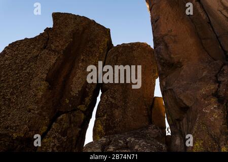 Ein Felskletterer ist durch ein Loch im Felsen an den Golden Cliffs auf dem North Table Mountain oberhalb von Golden, Colorado zu sehen. Stockfoto