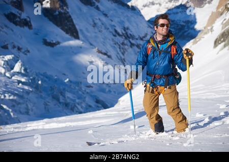 Lächelnder Skifahrer in blauer Jacke stand auf einer Gletscherabfahrt still Stockfoto