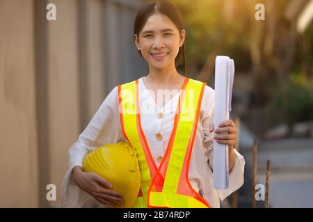 Woman Foreman Schutzanzug mit Schutzkleidung zur Durchführung von Baupläne für Baugrundgebäude Stockfoto