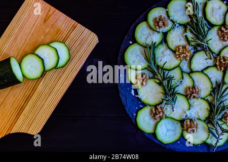 Carpaccio aus Zucchini mit Nüssen und Käse auf dunklem Holzhintergrund Stockfoto