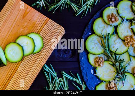 Carpaccio aus Zucchini mit Nüssen und Käse auf dunklem Holzhintergrund Stockfoto