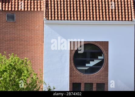 Weiße Fassade mit großem Rundfenster, mit dem man eine Treppe sehen kann Stockfoto