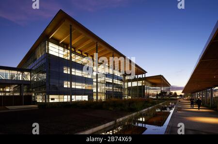 Fußgängerzugang zum Haupteingang in der Nacht. Jaguar Land Rover, Gaydon, Großbritannien. Architekt: Bennetts Associates Architects, 2019. Stockfoto