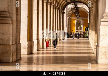 Lissabon, Portugal - 2. März 2020: Fußgänger, die den Gehweg unter dem Gebäude des Justizministeriums in der Nähe des Arco da Rua Augusta gehen Stockfoto