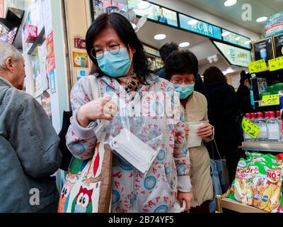 Die Menschen stehen bereit, um kostenlose chirurgische Masken aus einer Apotheke in Hongkong zu bekommen. Jede Person kann 3 Masken erhalten. Stockfoto