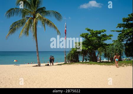 16.11.2019, Phuket, Thailand, Asien - Urlauber unter einer Palme am Strand von Karon Beach, einem beliebten Reiseziel für russische Touristen. [Automatisierte Übersetzung] Stockfoto