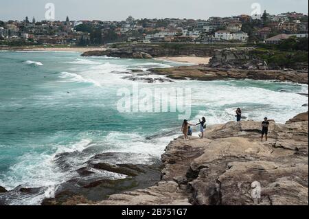 27.09.2019, Sydney, New South Wales, Australien - Touristen blicken von den Klippen am Tamarama Point ins Meer. Der Aussichtspunkt liegt am Küstenweg Bondi zum Coogee Walk. In der Ferne sehen Sie die Strände von Bronte und Tamarama Beach. [Automatisierte Übersetzung] Stockfoto